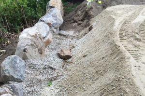 The driveway is reinforced with boulders and gravel